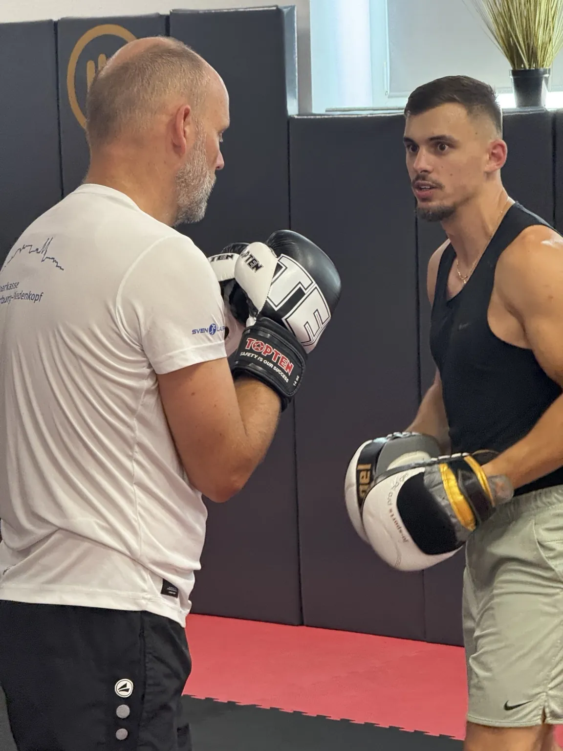 Ein Trainer erklärt einem Boxer beim Pratzentraining eine Technik im CONFIDENSE-Studio.